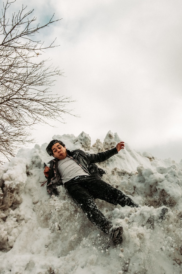 Shocked young male slides on his back down a wall of ice and snow. Photo by Jakob Rosen on Unsplash